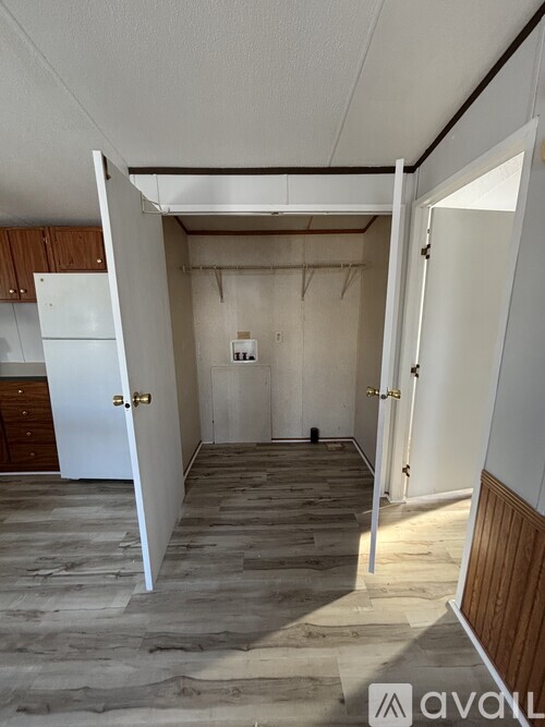 A room with a white door and a white refrigerator in the kitchen.