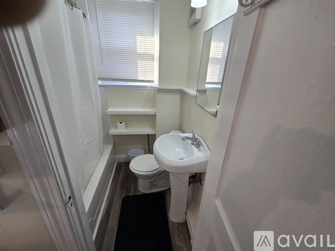 A small white bathroom with a toilet, sink, and mirror.