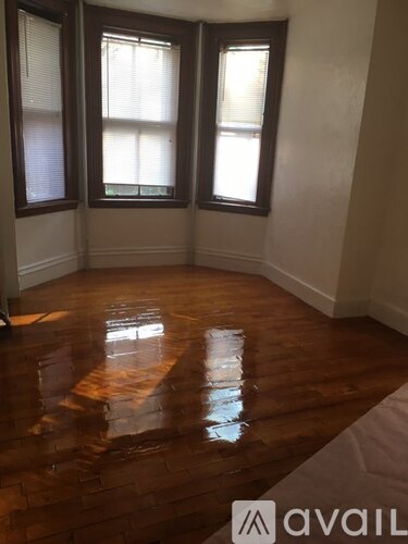 A room with wooden floors and three windows.