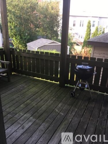 A patio with a black chair and a grill.