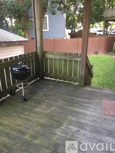 A wooden deck with a grill and a red mat.