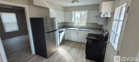 A kitchen with a black fridge and a black trash bin.