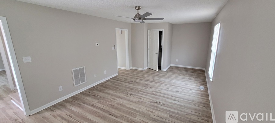 A spacious room with wood flooring and a ceiling fan.