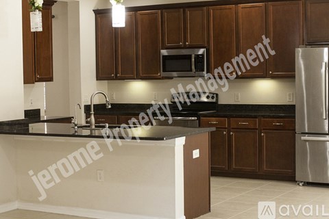 A kitchen with brown cabinets and a black countertop.
