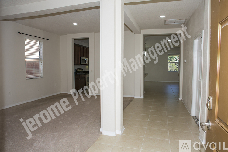 A spacious hallway with a door on the right and a window with blinds on the left.