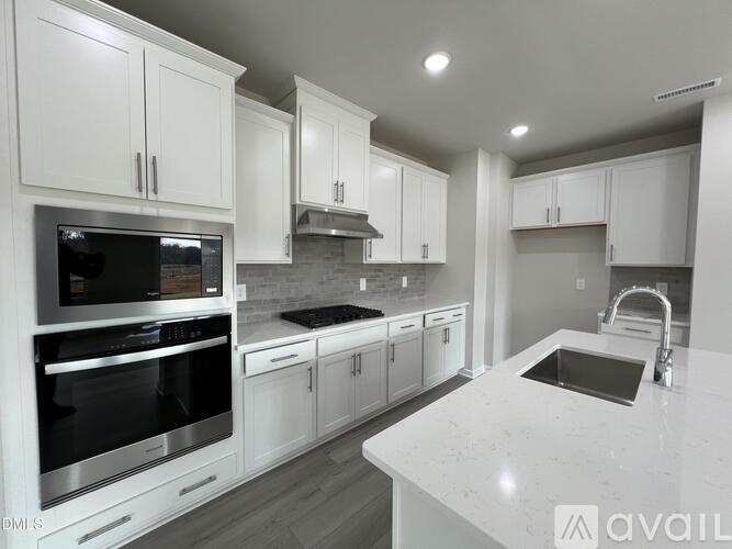 A modern kitchen with white cabinets and stainless steel appliances.