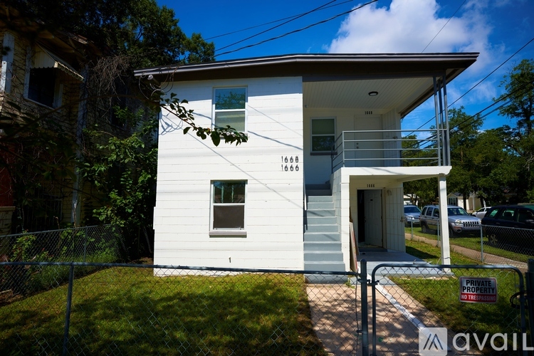 A small white house with a black fence and a sign that says "available".