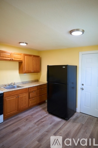 A kitchen with wooden cabinets and a black fridge.