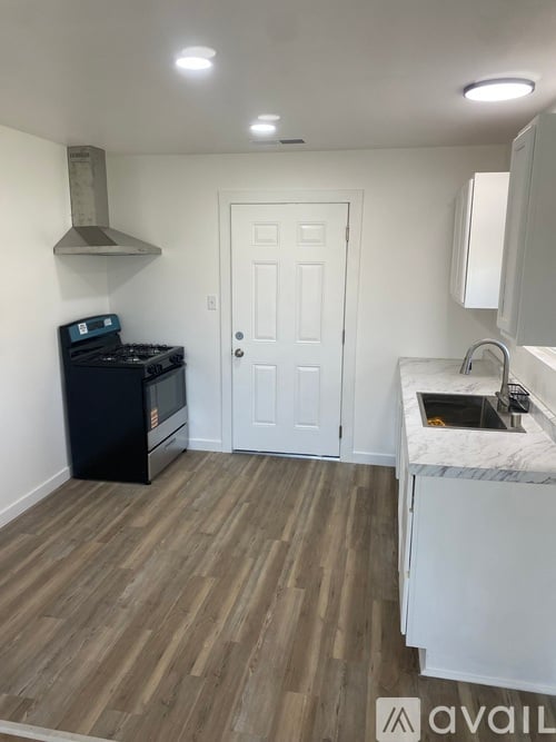 A kitchen with a black stove top oven and a white door.