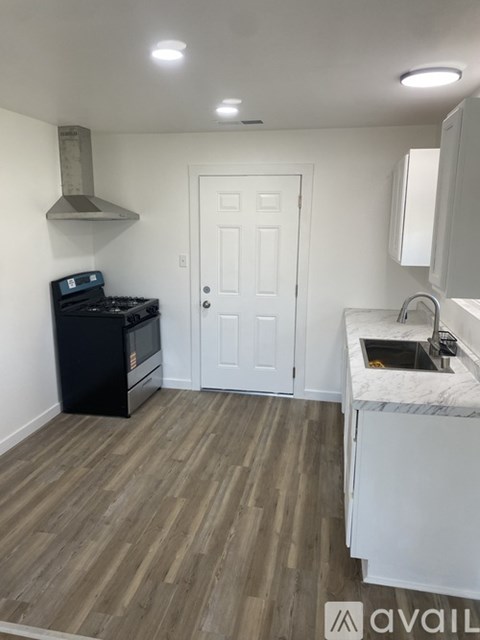 A kitchen with a black stove top oven and a white door.