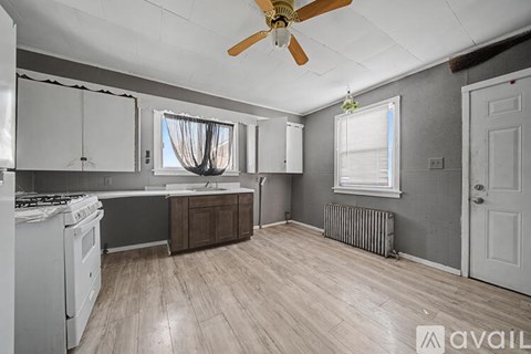 A kitchen with a white stove and wooden floors.