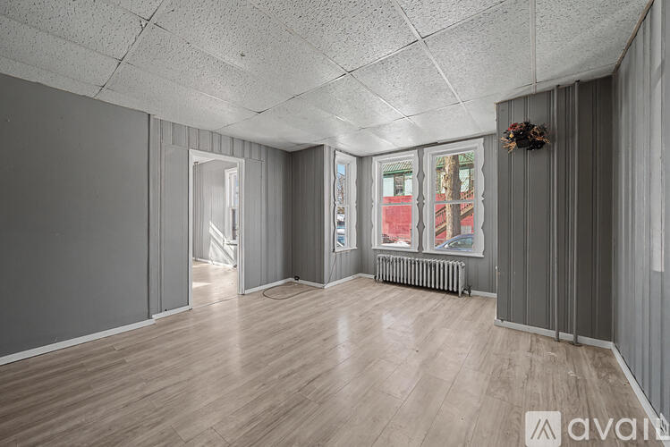 A room with wooden floors and a window with a view of a building outside.