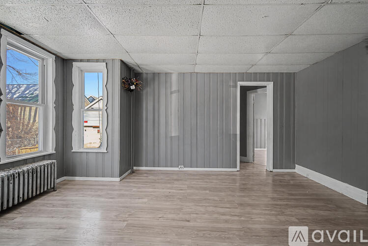 A room with grey walls and wooden flooring is available for rent.