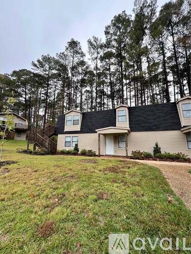 A house with a black roof is surrounded by trees.