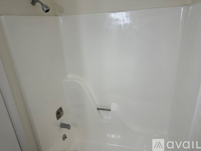 A white bathtub with a shower head and a faucet.