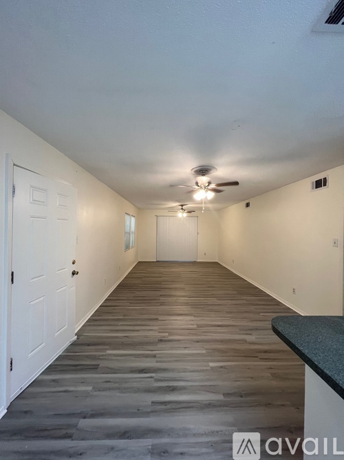 A long, empty hallway with a fan on the ceiling and doors on the left side.