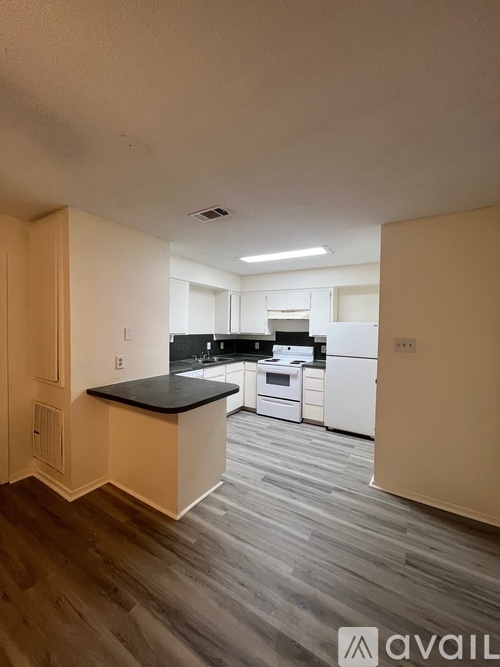 A kitchen with white appliances and a black countertop.