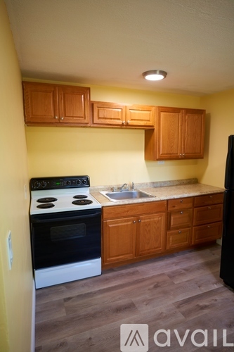 A kitchen with wooden cabinets and a black refrigerator.