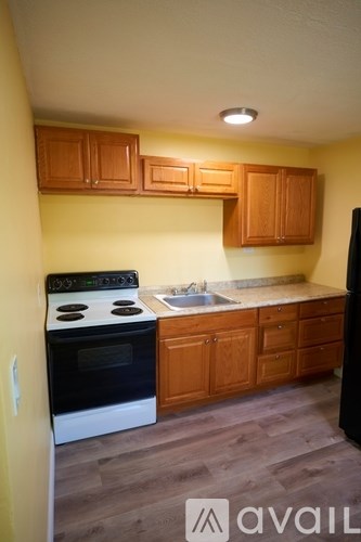 A kitchen with wooden cabinets and a black refrigerator.