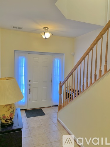 A lamp sits on a table in a room with a staircase.
