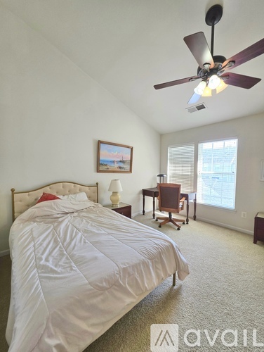 A bedroom with a large bed and a ceiling fan.