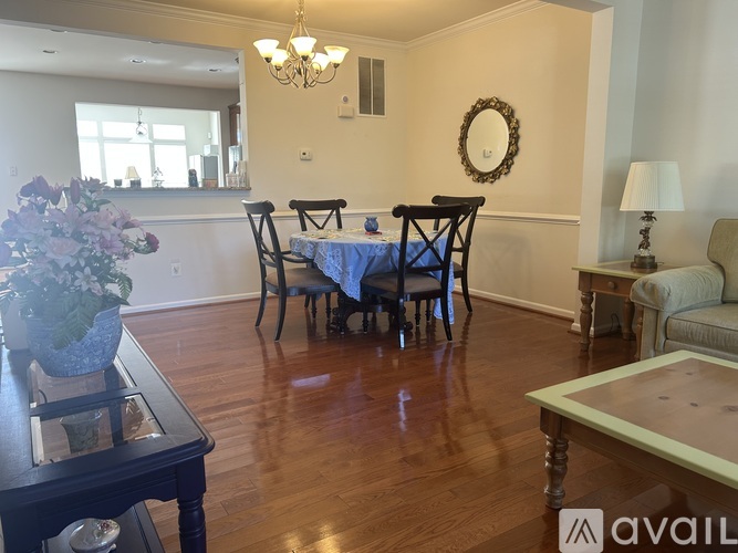A dining room with a table set for six and a chandelier hanging from the ceiling.