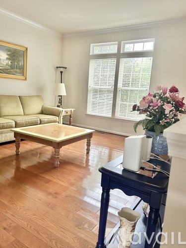 A living room with a tan couch, a coffee table, and a painting on the wall.