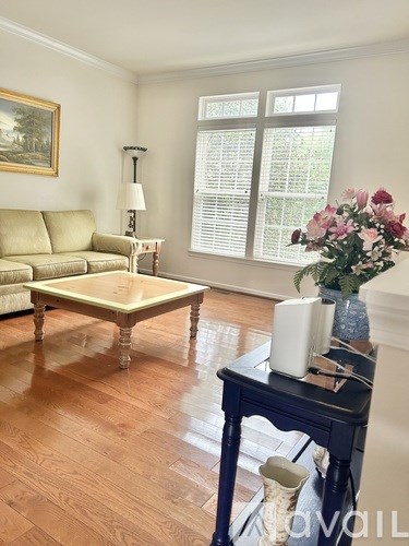 A living room with a tan couch, a coffee table, and a painting on the wall.