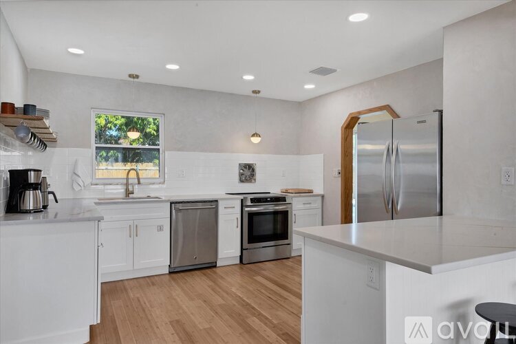 A kitchen with white cabinets and a wooden floor.