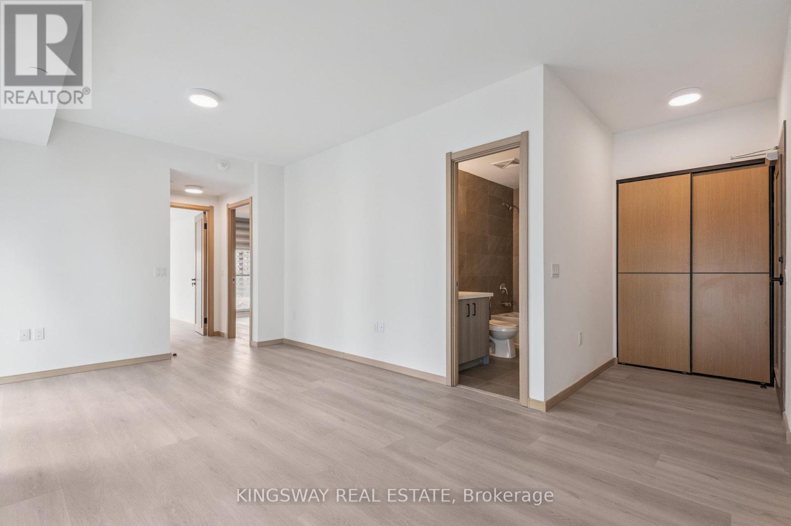 A spacious room with a toilet and sink visible through an open door.