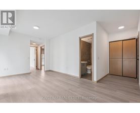 A spacious room with a toilet and sink visible through an open door.