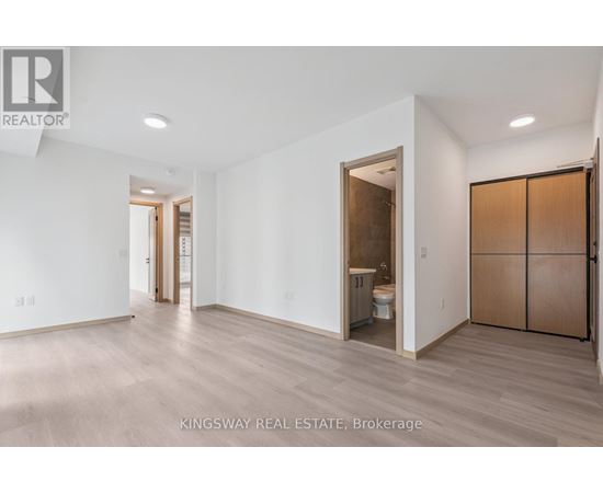 A spacious room with a toilet and sink visible through an open door.