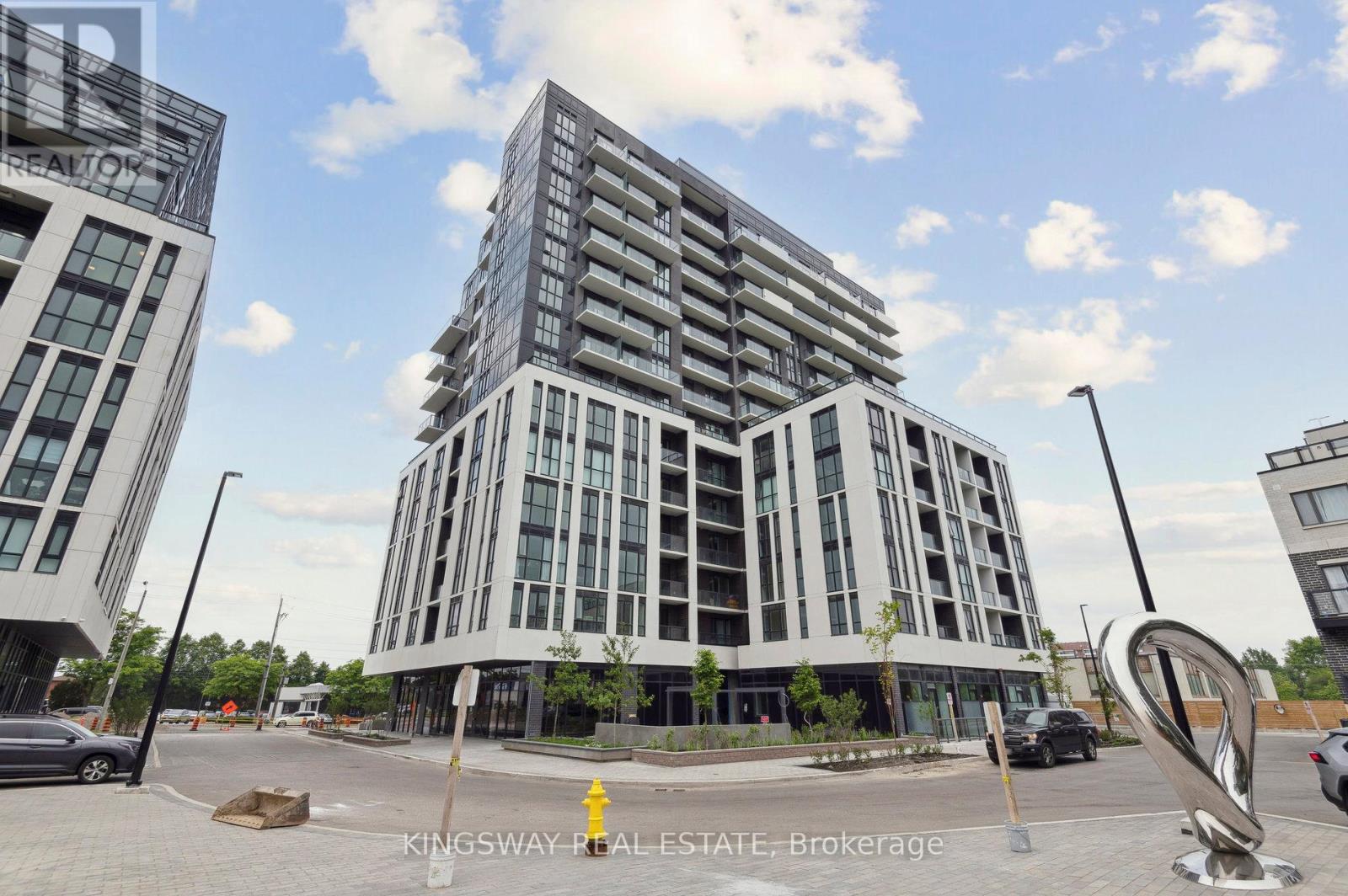A modern multi-story building with a parking lot in front.