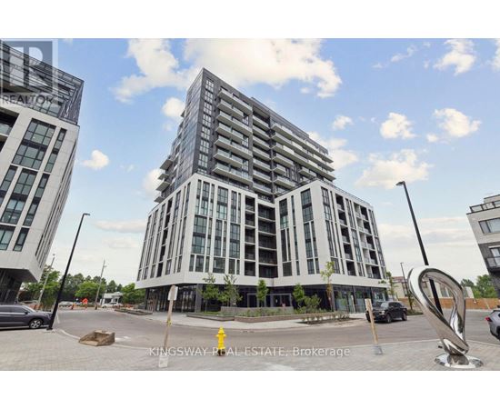 A modern multi-story building with a parking lot in front.