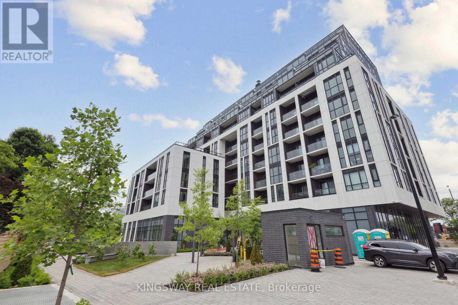 A modern multi-story building with a parking lot in front.