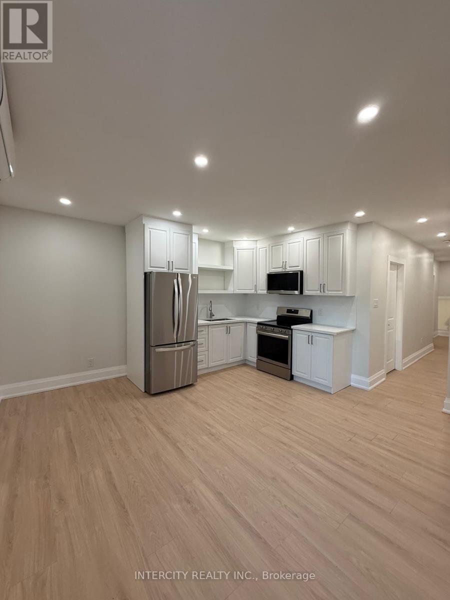 A well-lit, empty kitchen with white cabinets and a wooden floor.