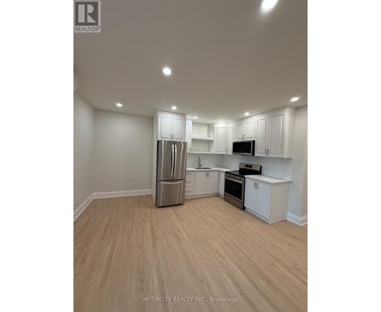 A kitchen with white cabinets and a wooden floor.