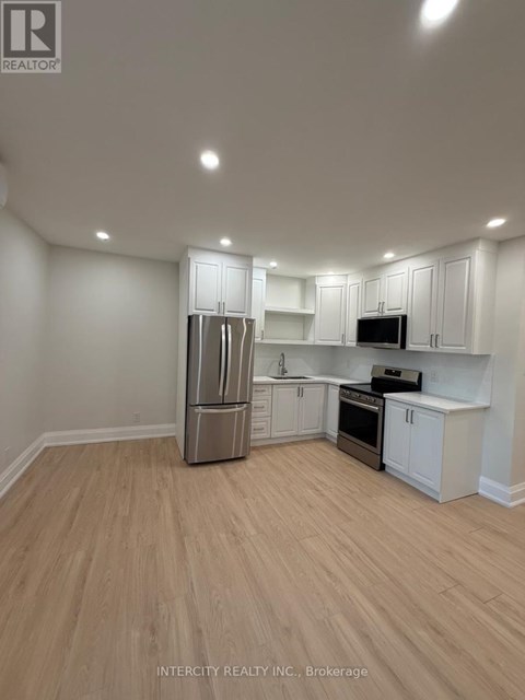 A kitchen with white cabinets and a wooden floor.