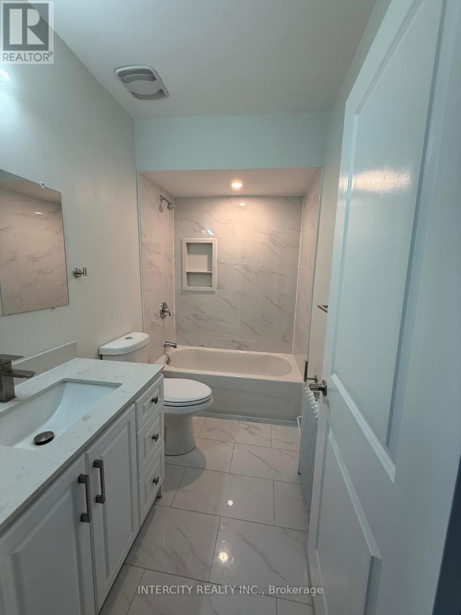 A bathroom with a tub, toilet, and sink.