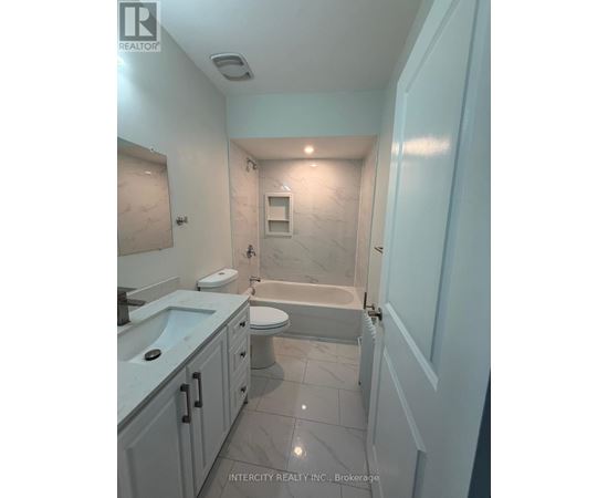 A bathroom with a tub, toilet, and sink.