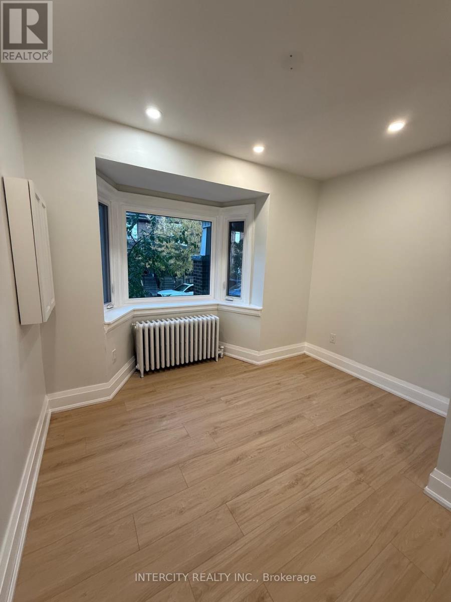 A room with wooden flooring and a window with a view of trees.