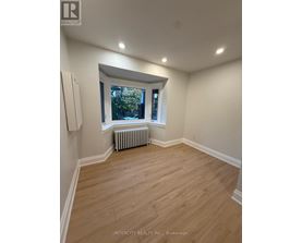 A room with wooden flooring and a window with a view of trees.