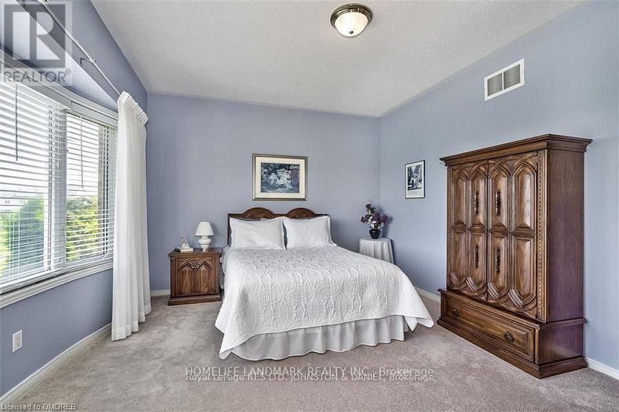A bedroom with a bed, nightstand, and a wooden armoire.