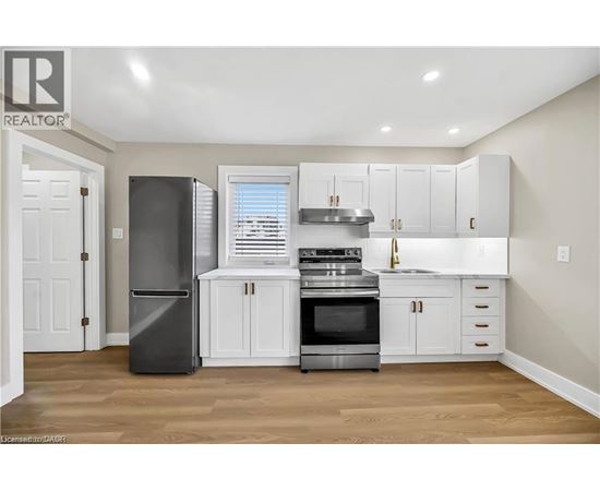 A kitchen with white cabinets and a black refrigerator.
