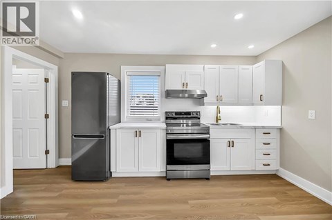 A kitchen with white cabinets and a black refrigerator.