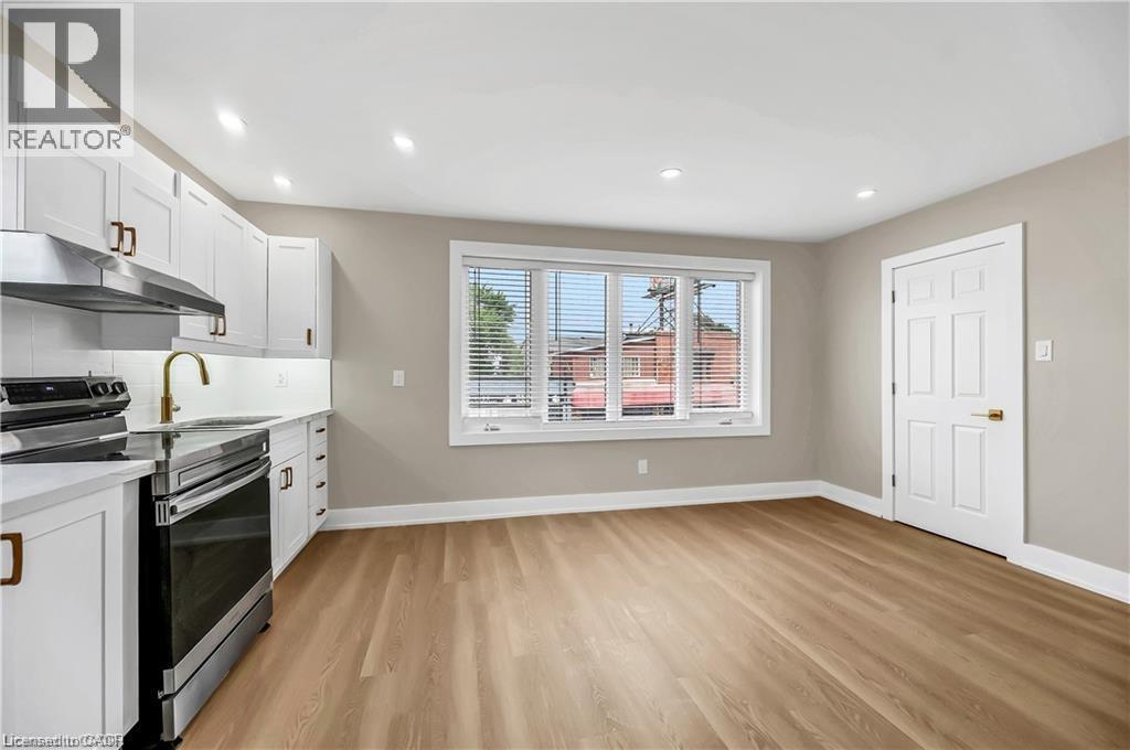 A kitchen with white cabinets and a window with blinds.