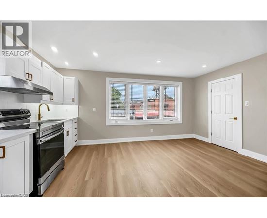 A kitchen with white cabinets and a window with blinds.