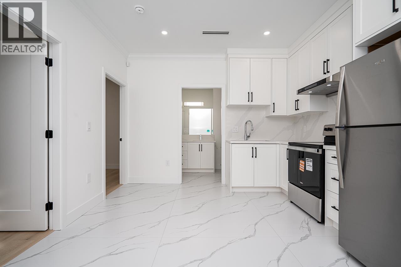A modern kitchen with white cabinets and a marble floor.