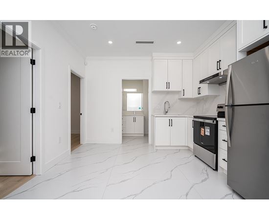 A modern kitchen with white cabinets and a marble floor.