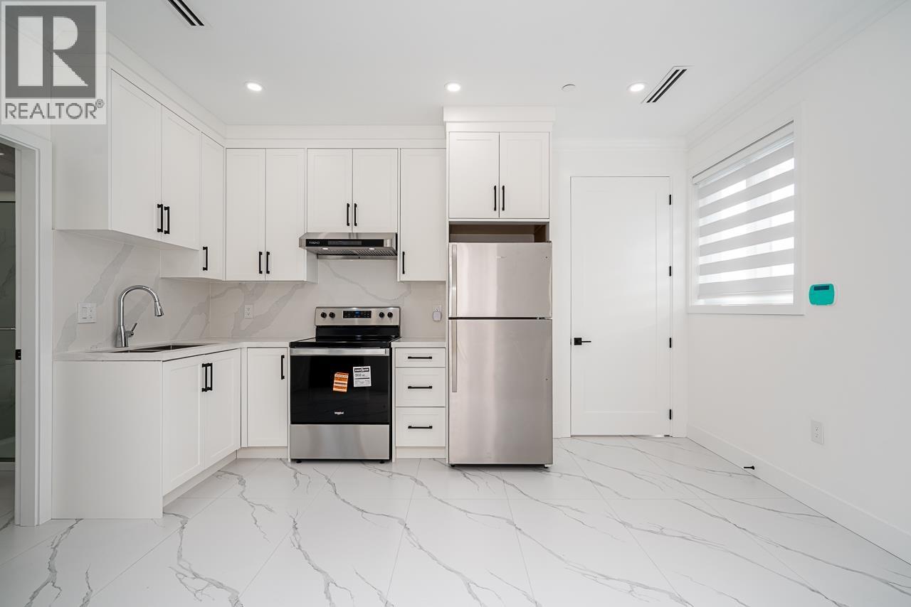 A modern kitchen with white cabinets and marble flooring.